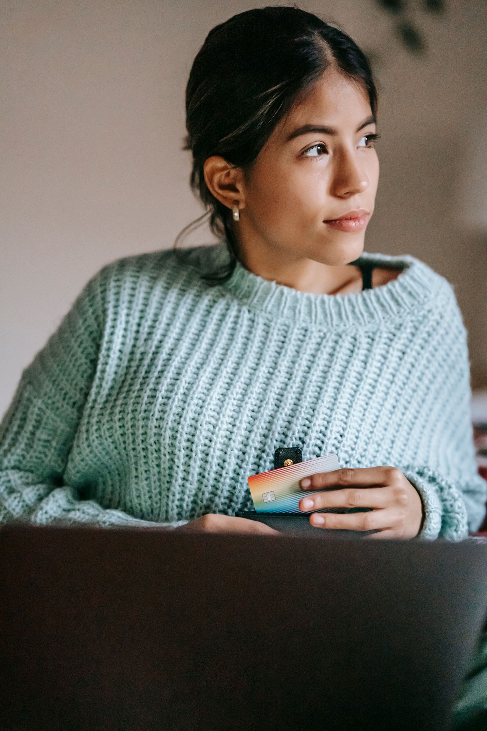 Young Indian woman checking cashback rewards on phone with credit card