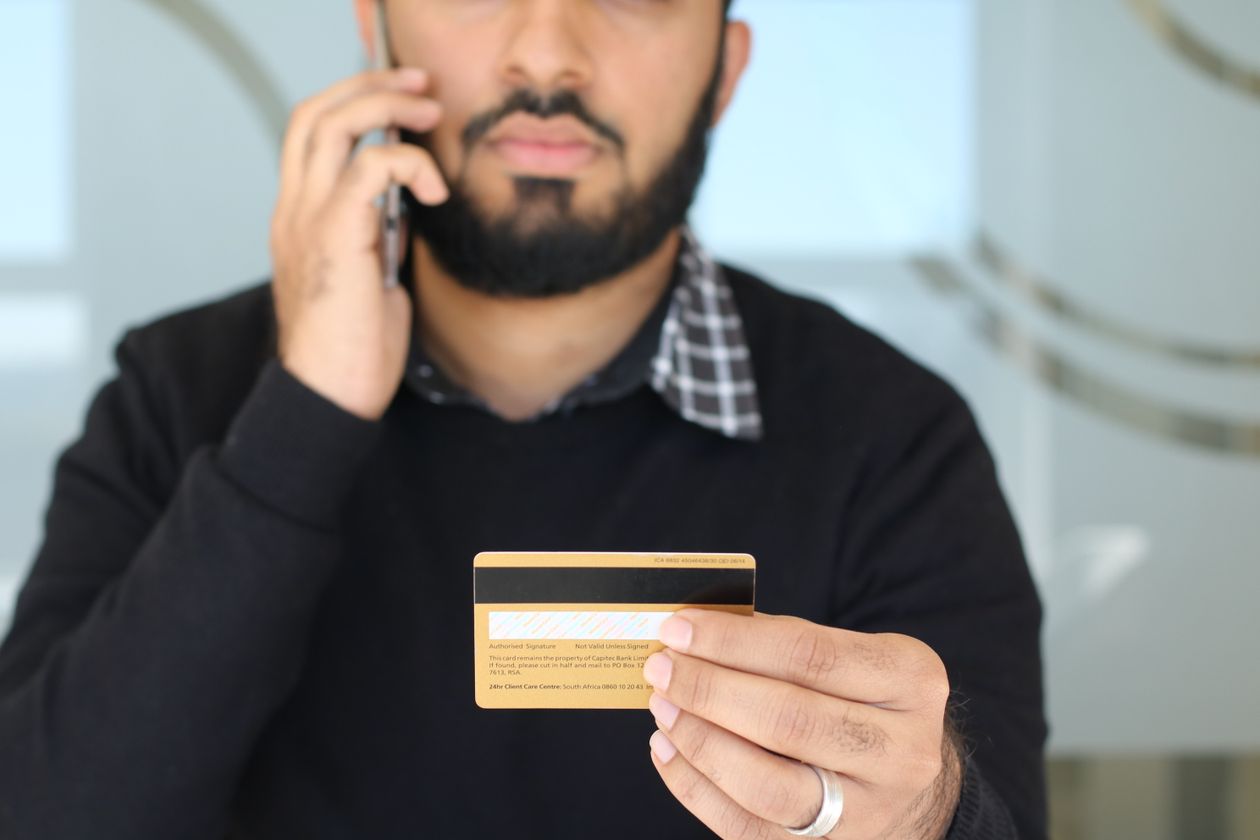 Young Indian man holding a credit card while on the phone